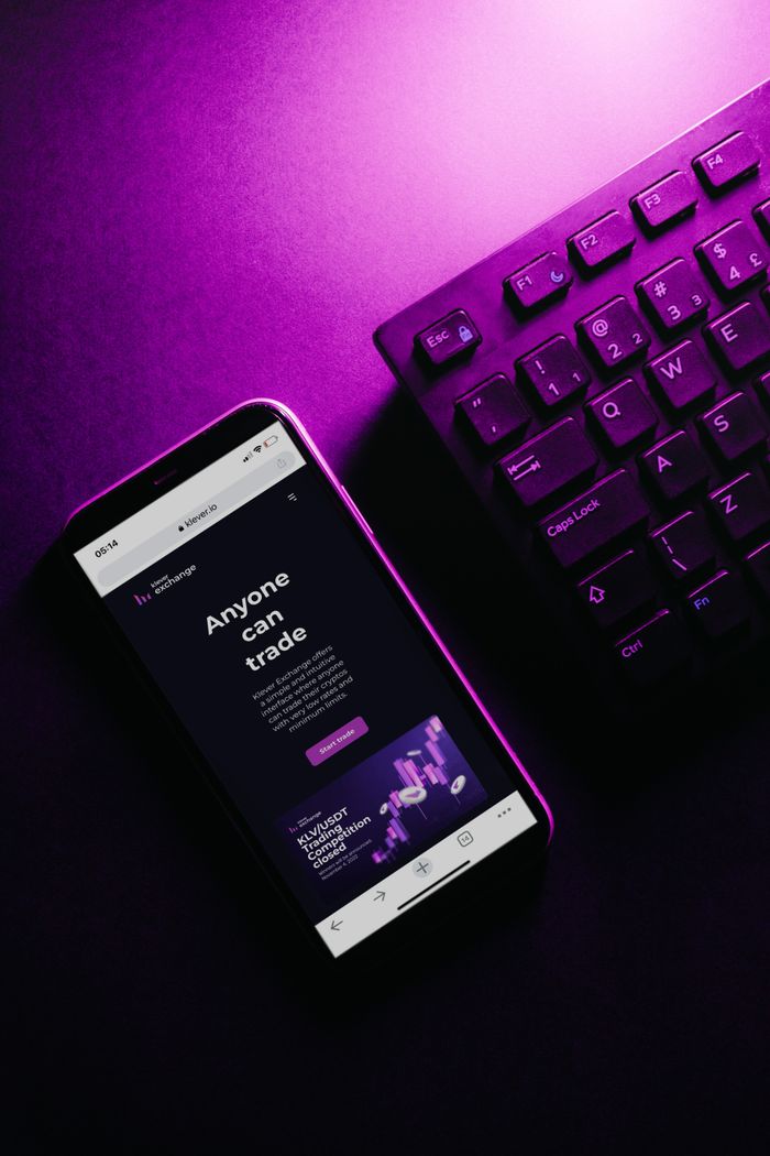 why-choose-us-02 Close-up of a smartphone and keyboard under vibrant purple lighting, showcasing modern tech aesthetics.