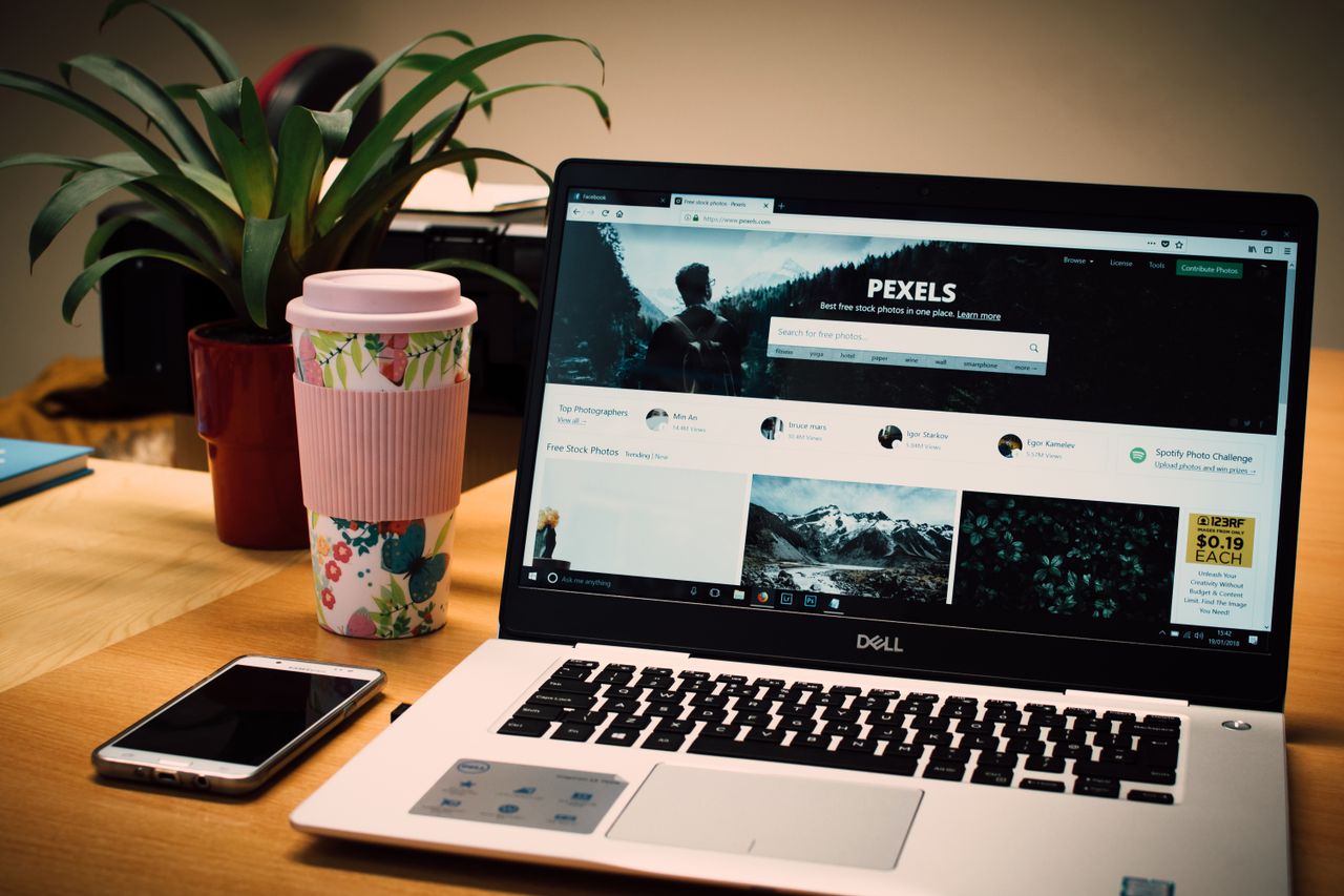 our-story-01 A tidy desk setting with a laptop showing a stock photo website and a smartphone.